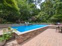 Inviting in-ground pool with a stone surround, patio, lounge chairs, and lush landscaping for a serene outdoor oasis at 121 Flint Point Ln, Holly Springs, NC 27540