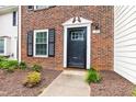 Close-up of brick townhome entrance with black door, white trim, and landscaped walkway at 129 Assembly Ct, Cary, NC 27511