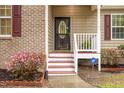 Inviting front porch with red stairs, white railings, brick accents, and colorful flowering plants at 1510 Bungalow Ave, Durham, NC 27703