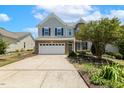 Inviting two-story home featuring a two-car garage, manicured lawn, and mature trees at 2128 Feather Ridge Dr, Holly Springs, NC 27540