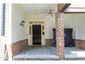 Inviting front porch featuring brick accents, a ceiling fan, and a stylish black front door at 2800 Charleston Oaks Dr, Raleigh, NC 27614