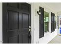 Close-up of the front door with black paint, side windows, and classic hardware at 366 E Smithfield St, Angier, NC 27501