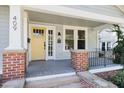 Inviting front porch featuring brick columns, grey painted floors and a bright yellow front door at 409 N Hyde Park Ave, Durham, NC 27703
