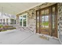 Inviting covered front porch with stone accents, a cozy porch swing, and a beautifully crafted wood door at 421 Gilpin Way, Cary, NC 27519