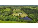 An aerial view of a property featuring a house, pond, large grassy area, and surrounding forest at 5200 Mrs Fuller Rd, Mebane, NC 27302