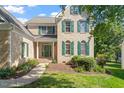 Beautiful brick home featuring well-manicured landscaping, a covered porch, and decorative green shutters at 9112 Mission Hills Ct, Raleigh, NC 27617