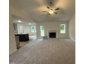 Spacious living room featuring plush carpeting, a fireplace, and ample natural light with an open view to the kitchen at 151 Oakfield Trace Dr, Four Oaks, NC 27524