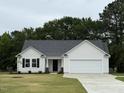 Inviting one-story home with a classic white facade, black trim, and an attached two-car garage at 188 Oakfield Trace Dr, Four Oaks, NC 27524