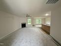 Bright and open living room with a fireplace, carpet flooring, and a view into the kitchen area at 188 Oakfield Trace Dr, Four Oaks, NC 27524
