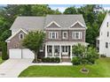Beautiful two-story brick home with a covered front porch, complemented by mature trees and green lawn at 213 Preatonwood Dr, Apex, NC 27539