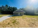 Inviting single-story home with a covered porch, set against a backdrop of lush greenery under a bright sky at 300 Saturn St, Dunn, NC 28334