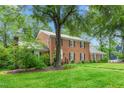 Side view of a well-maintained brick home with lush greenery and mature trees at 3027 Truitt Dr, Burlington, NC 27215
