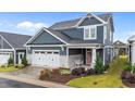Attractive two-story home featuring a covered front porch, a two-car garage, and colorful flower beds at 33 Davidson St, Clayton, NC 27527
