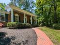 Inviting brick pathway leading to a home's covered porch with classic columns and a manicured lawn at 3421 Angus Rd, Durham, NC 27705