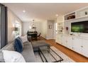 Cozy living room featuring hardwood floors, a large sectional sofa, and custom built-in shelving at 3421 Angus Rd, Durham, NC 27705