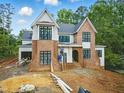 Two-story home featuring a brick facade, light gray siding and black-framed windows surrounded by a landscaped yard at 5013 Coronado, Raleigh, NC 27609