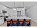 New kitchen boasts white cabinets, stainless appliances, pendant lights, and a blue island with seating at 5041 Lundy Dr # 102, Raleigh, NC 27606