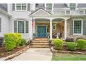 This home has a cozy front porch with stone pillars and a beautiful blue door perfect for relaxation at 5405 Bluet Ct, Holly Springs, NC 27540