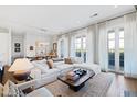 Bright living room with a large white sectional sofa, elegant curtains, and balcony access at 620 Wade Ave # 505, Raleigh, NC 27605