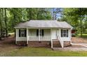 Inviting single-story home with light siding, dark shutters, and a quaint front porch, surrounded by mature trees at 627 Gaslight Trl, Wendell, NC 27591