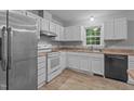 Bright kitchen featuring white cabinetry, laminate countertops, stainless steel refrigerator, and wood-look flooring at 627 Gaslight Trl, Wendell, NC 27591