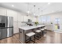 Well-lit kitchen with a large island, stainless steel appliances, white cabinets, and modern pendant lighting at 66 Arlie Ln, Lillington, NC 27546