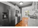 Well-lit kitchen showcasing stainless steel refrigerator, modern cabinets, granite countertops, and wood floors at 8231 Allyns Landing Way # 101, Raleigh, NC 27615