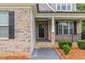 Close up of a brick home's front porch with black door, railing and manicured flower beds at 90 Starwood Dr, Garner, NC 27529
