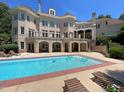 Beautiful backyard with large pool, patio area, lounge chairs, and a multi-level brick home at 1000 Clovelly Ct, Raleigh, NC 27614