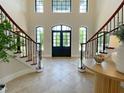 Grand foyer with tiled floor, staircase, and transom windows over a black front door at 1000 Clovelly Ct, Raleigh, NC 27614