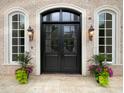 Elegant brick home entrance featuring a black double door, arched windows, and decorative planters at 1000 Clovelly Ct, Raleigh, NC 27614
