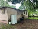 View of backyard with peeling exterior, discarded refrigerator, and old grill at 1002 Loius St, Burlington, NC 27217