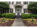 Charming home entrance with a brick walkway, manicured bushes, and decorative front door at 1002 Vance St, Raleigh, NC 27608