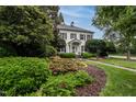 Elegant white brick home featuring lush landscaping, mature trees, and a well-maintained lawn at 1002 Vance St, Raleigh, NC 27608