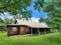 One-story rustic cabin with brown exterior, metal roof, and a lush green yard at 111 Matthews Mill Pond Rd, Angier, NC 27501
