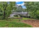 Traditional home with mature trees, manicured bushes and landscaping, and attached garage on a lush, green lot at 1311 Theodore Ln, Durham, NC 27703