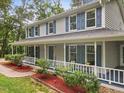 Inviting two-story home showcasing charming architectural details, a wrap-around porch, and lush landscaping at 14 Gloucester Ct, Durham, NC 27713