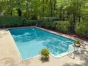 Refreshing in-ground pool surrounded by lush greenery and concrete deck, perfect for outdoor relaxation and entertainment at 14 Gloucester Ct, Durham, NC 27713