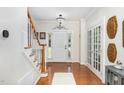Bright foyer with hardwood floors, a staircase with white railing, and a view of the front door at 1603 Timber Wolf Dr, Durham, NC 27713