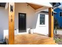Inviting front porch with wooden deck, elegant door, stylish lighting, and potted plants at 18 W Academy St, Wendell, NC 27591