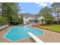 Backyard pool with diving board, deck area, surrounded by mature trees and landscaping at 1817 Foxbrook Dr, Raleigh, NC 27603