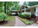 Inviting front entrance with a brick walkway and garden, leading to a modern home with large windows at 2004 Flagstone Pl, Raleigh, NC 27612