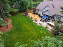 Aerial view of a backyard with a lush lawn, mature trees, and an inviting stone patio at 201 Margaret Mann Way, Pittsboro, NC 27312