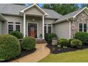 Inviting front entrance with a covered porch, stone accents, and mature landscaping, creating a warm welcome at 2208 Wimberly Woods Dr, Sanford, NC 27330