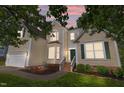 Two-story home featuring cream siding, a green front door, and attached garage at twilight at 2412 Colony Woods Dr, Apex, NC 27523
