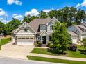 Charming home exterior featuring a three-car garage, landscaped front yard, and inviting front porch at 2538 Tuffeto, Apex, NC 27502