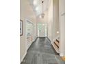 Bright foyer featuring a high ceiling, chandelier, stone tile floor, and staircase at 2606 Sherbrooke Dr, Durham, NC 27712