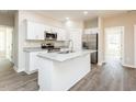 Modern kitchen features white cabinets, stainless steel appliances, and a spacious island with a sink at 2807 Ricolden Trl, Elon, NC 27244