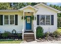Inviting blue front door with decorative hanging ferns, complemented by manicured landscaping and window shutters at 364 Chinaberry Ln, Angier, NC 27501