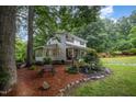 An alternate view of the home showing a sunroom and well landscaped yard with various greenery at 4777 Helena Moriah Rd, Rougemont, NC 27572
